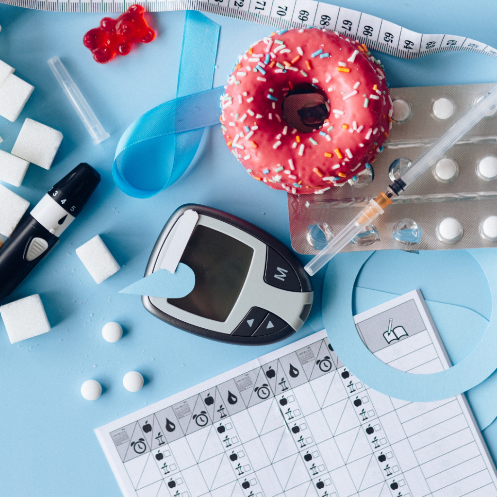 Diabetes-Symbolik: Donut, Glukosemessgerät, Spritze, blaue Schleife auf blauem Hintergrund. Zucker und Gesundheit im Fokus.