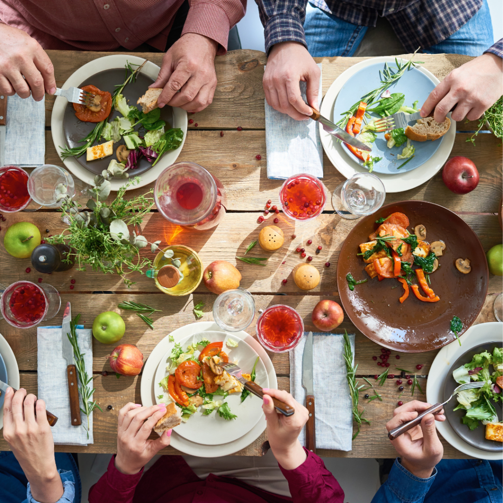 Gesellige Tischrunde mit buntem, frischem Essen und Getränken. Einladende Atmosphäre voller Freude und Gemeinschaft.
